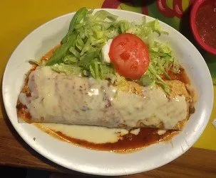 Burrito Loco plated with lettuce, tomato and sour cream